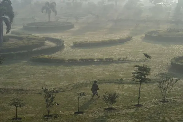 A woman walks in a public park amid smoggy conditions in Lahore on November 24, 2021. (Photo by Arif Ali/AFP Photo)