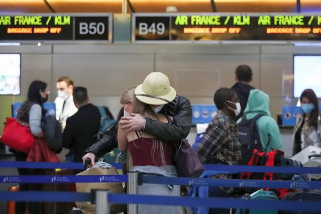 People hug as they wait in the check-in line for Air France/KLM at the Tom Bradley International Terminal at Los Angeles International Airport in Los Angeles, California, USA, 22 December 2021. The Omicron variant of the coronavirus pandemic is becoming the dominant strain in many countries as case numbers spike around the world. (Photo by Caroline Brehman/EPA/EFE)