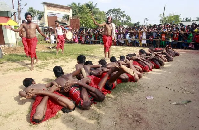 A Hindu priest blesses ritually bound devotees lying on the ground during a ritual as part of the annual Shiva Gajan religious festival at Pratapgarh, on the outskirts of Agartala, India, April 13, 2016. Hundreds of faithful devotees offer sacrifices and perform acts of devotion during the festival in the hopes of winning the favour of Hindu god Shiva and ensuring the fulfillment of their wishes, and also to mark the end of the Bengali calendar year. (Photo by Jayanta Dey/Reuters)