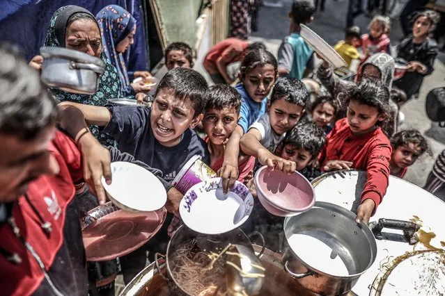 Palestinian children, deprived of the basic necessities of life, including basic food supplies, wait in line to receive food distributed by charity organizations as Israeli attacks continue in Khan Yunis, Gaza on April 14, 2024. (Photo by Ali Jadallah/Anadolu via Getty Images)