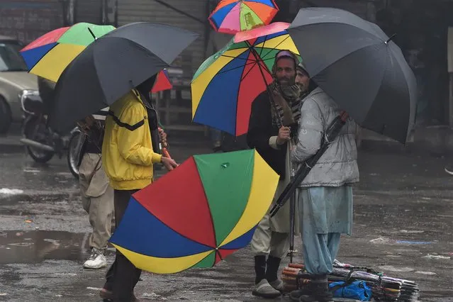 Vendors selling umbrellas wait for customers along a street during a rainy day in Lahore on January 7, 2022. (Photo by Arif Ali/AFP Photo)
