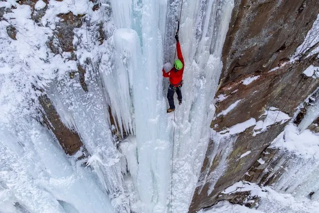 An aerial photo shows a climber on a rock wall covered with ice pillars during the Sandstone Ice Climbing Festival at Robinson Ice Park in Sandstone, Minnesota, on January 8, 2022. (Photo by Kerem Yucel/AFP Photo)