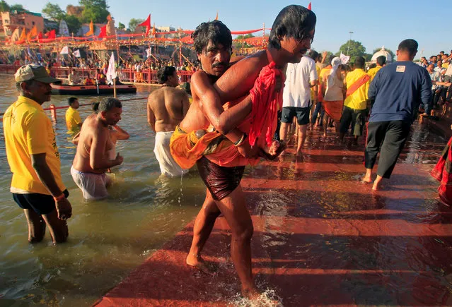 A Hindu devotee carries his disabled friend after taking a holy dip in the waters of the river Shipra during the Simhastha Kumbh Mela in Ujjain, India, April 22, 2016. (Photo by Jitendra Prakash/Reuters)