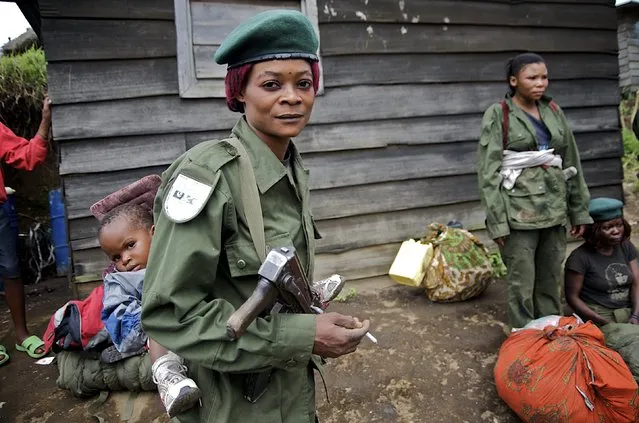 A government soldier carries her infant on her back at Mushake in eastern Congo, January 26, 2009. Congolese Hutu rebels said on Sunday they had clashed for the first time with a Rwandan-Congolese force deployed to crush them and civilians expressed fears they would be caught up in the violence. (Photo by Alissa Everett/Reuters)