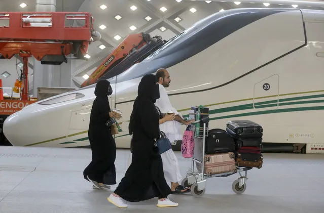 Pilgrims on their way to Mecca walk past the Haramain High-Speed Railway train in the holy city of Medina, Saudi Arabia, Thursday, August 8, 2019. Hundreds of thousands of Muslims have arrived in the kingdom to participate in the annual hajj pilgrimage, which starts Friday, a ritual required of all able-bodied Muslims at least once in their life. (Photo by Amr Nabil/AP Photo)