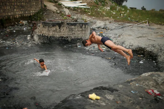 An Iraqi boy jumps at a sulfur pond at Hammam al-Alil city south of Mosul, Iraq April 3, 2017. This oasis of leisure now coexists, however, with camps housing more than 30,000 of the people displaced in the region by the campaign to dislodge Islamic State from Mosul, its the last major city stronghold in Iraq. (Photo by Suhaib Salem/Reuters)