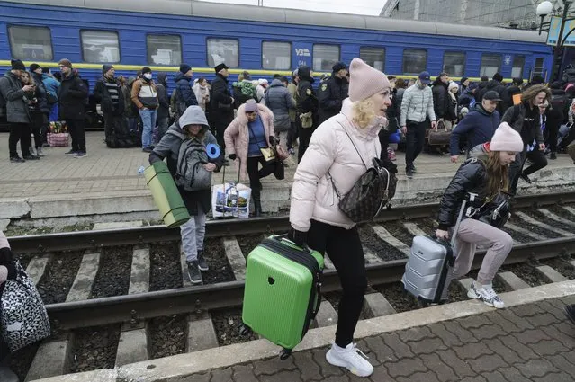 People gather to catch a train and leave Ukraine for neighboring countries at the railway station in Lviv,western Ukraine, Saturday, February 26, 2022. The U.N. refugee agency says nearly 120,000 people have so far fled Ukraine into neighboring countries in the wake of the Russian invasion. The number was going up fast as Ukrainians grabbed their belongings and rushed to escape from a deadly Russian onslaught. (Photo by Mykola Tys/AP Photo)