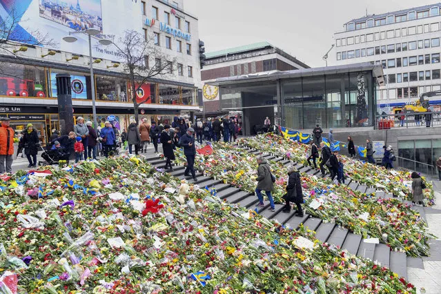 People look at the flowers left near the Ahlens department store in central Stockholm on Wednesday April 12, 2017. Rakhmat Akilov, a 39-year-old Uzbek man, has pleaded guilty to a terrorist crime after ramming a stolen beer truck into the crowd of afternoon shoppers outside the upmarket Ahlens store on Friday. (Photo by Fredrik Sandberg/TT News Agency via AP Photo)