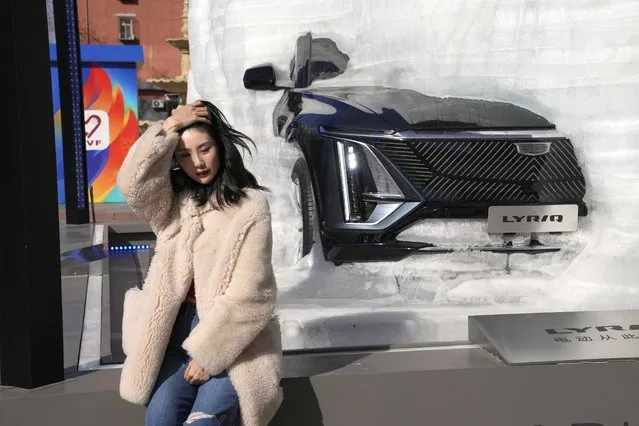 A woman sits near a car encased in real ice as part of a promotional stunt on Friday, March 4, 2022, in Beijing. (Photo by Ng Han Guan/AP Photo)