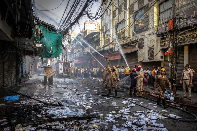 Firefighters try to extinguish a fire in some textile shops at a market area in the old quarters of Delhi, India, June 13, 2024. (Photo by Adnan Abidi/Reuters)