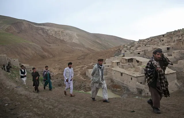 In this Sunday, May 4, 2014 photo, Afghan men walk near the site of Friday's landslide that buried Abi-Barik village in Badakhshan province, northeastern Afghanistan. Stranded and with no homes, many of the families have struggled to get aid. Some have gone to nearby villages to stay with relatives or friends, while others have slept in tents provided by aid groups. The unlucky ones have slept outside. (Photo by Massoud Hossaini/AP Photo)