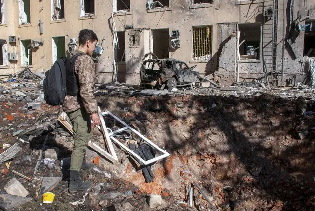 A man looks at a hole after shelling in the Eastern-Ukrainian city of Kharkiv, Ukraine, 22 March 2022. The city of Kharkiv, Ukraine's second-largest, has witnessed repeated airstrikes from Russian force. Russian troops entered Ukraine on 24 February resulting in fighting and destruction in the country, and triggering a series of severe economic sanctions on Russia by Western countries. (Photo by Vasiliy Zhlobsky/EPA/EFE)