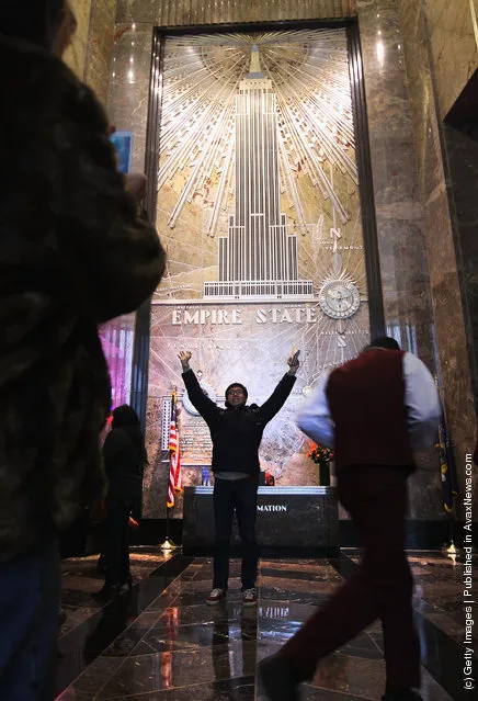 A tourist poses for photos inside the lobby of the Empire State Building