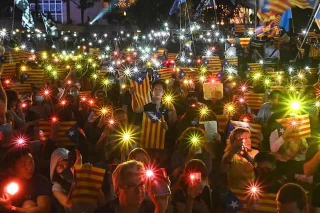People hold Catalan pro-independence “Estelada” flags and light up their mobile phones during a Hong Kong-Catalonia solidarity assembly in Central district in Hong Kong on October 24, 2019. (Photo by Philip Fong/AFP Photo)