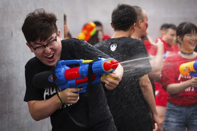 In this Saturday, July 4, 2015 photo, a player fires his water gun as he participates in a battle maze in Beijing. Players, also cooling off from the summer heat, divided into teams of aliens, humans, and zombies to soak each other with water guns in the large outdoor maze, which organizers said was inspired by the online and mobile video games that are increasingly popular with China's youth. (Photo by Mark Schiefelbein/AP Photo)