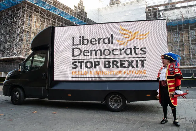 Town crier Tony Appleton stands in front of a digital screen as it displays the new Liberal Democrat election campaign slogan on the back of a van outside the Houses of Parliament at Old Palace Yard on October 31, 2019 in London, England. (Photo by Leon Neal/Getty Images)