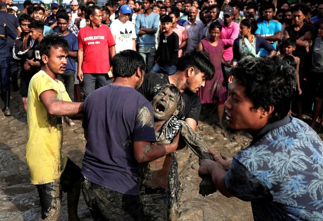 A man reacts as he sees the body of his father in the flooded area along the bank of the overflowing Bagmati River following heavy rains in Kathmandu, Nepal on July 31, 2024. (Photo by Navesh Chitrakar/Reuters)