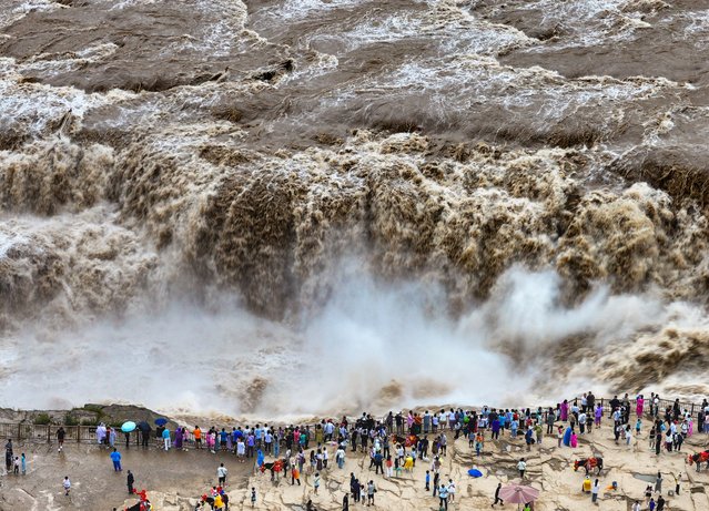 Tourists watch roaring torrent carrying a large amount of yellow sediment at the Hukou Waterfall on the Yellow River on August 15, 2024 in Yan'an, Shaanxi Province of China. (Photo by VCG/VCG via Getty Images)