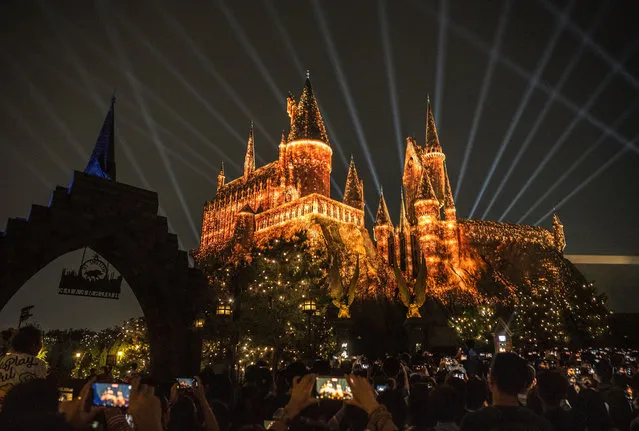 People watch a light show over Hogwarts Castle in the Wizarding World of Harry Potter attraction at Universal Studios Beijing on September 23, 2021 in Beijing, China. Universal Studios Beijing Resort which features attractions from some of the company's famous film brands including Harry Potter, Transformers, Minions Kung Fu Panda and others as well as restaurants, hotels and a city-walk, officially opened to sell-out crowds on September 20th. It is Universal Studios' fifth global theme park, and is a joint venture between state-owned Beijing Shouhuan Cultural Tourism Investment Co. and Universal Parks & Resorts, a business unit of Comcast NBCUniversal. The park opens at a time of strained U.S. and China relations. (Photo by Kevin Frayer/Getty Images)