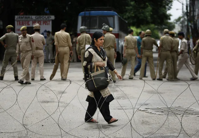 An Indian woman walks near a barbed wire set up as a road blockade by Indian police during a shutdown in Jammu, India, Saturday, August 1, 2015. Protesters on Saturday clashed with policemen on the second consecutive day of a three-day shutdown over the demand for the establishment of All India Institute of Medical Sciences or AIIMS in the region. (Photo by Channi Anand/AP Photo)