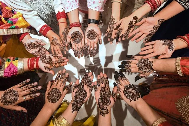 Women pose a photo after applying henna tattoos on their hands during “Chand Raat” or 'Night of the Moon' in Kathmandu on May 1, 2022, on the eve of the Muslim Eid al-Fitr festival. (Photo by Prakash Mathema/AFP Photo)