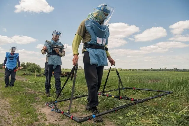 Volunteers of Danish NGO demonstrate a search process of explosive devices with help of an Ebinger large loop metal detector, as Russia's attack on Ukraine continues, outside the town of Ichnia, in Chernihiv region, Ukraine on June 7, 2022. (Photo by Vladyslav Musiienko/Reuters)