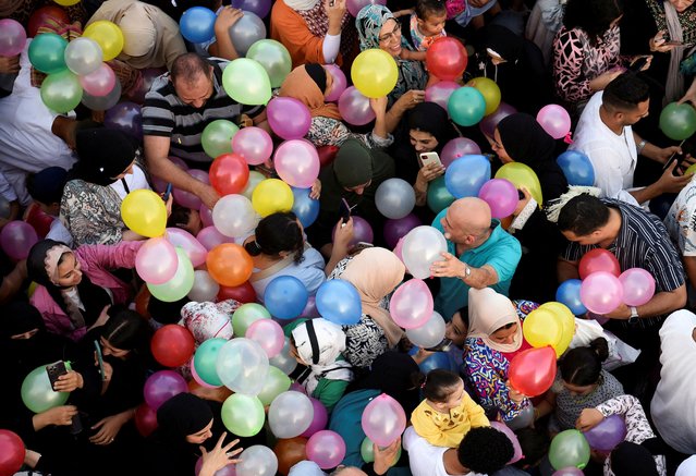 People attempt to catch balloons released after an Eid al-Adha prayer at a public park, outside El-Seddik Mosque in Cairo, Egypt, on June 16, 2024. (Photo by Mohamed Abd El Ghany/Reuters)