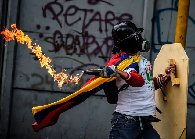 An opposition activist clashes with the police during a march towards the Supreme Court of Justice (TSJ) in an offensive against President Maduro and his call for Constituent Assembly in Caracas on July 22, 2017. The Legislative power, controlled by the opposition, appointed Friday a parallel supreme court in a public session claiming the TSJ judges had been illegally appointed by the parliament’s former pro- government majority. (Photo by Juan Barreto/AFP Photo)