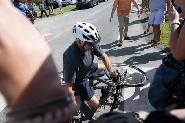 US President Joe Biden falls off his bicycle as he approaches well-wishers following a bike ride at Gordon's Pond State Park in Rehoboth Beach, Delaware, on June 18, 2022. (Photo by Saul Loeb/AFP Photo)