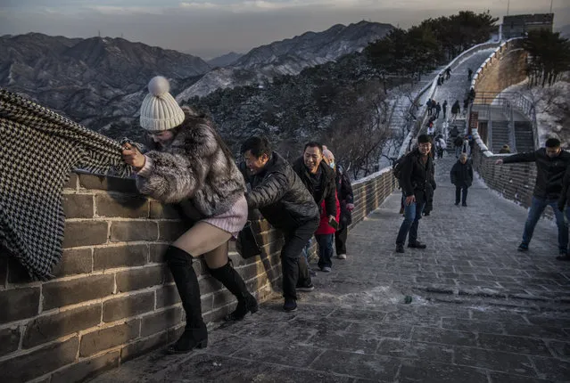 A Chinese tourist uses the scarf of a friend as she is helped while she and others struggle to climb in the wind on an icy section of the Great Wall at Badaling, on a cold day after a snowfall on November 30, 2019 in Beijing, China. (Photo by Kevin Frayer/Getty Images)
