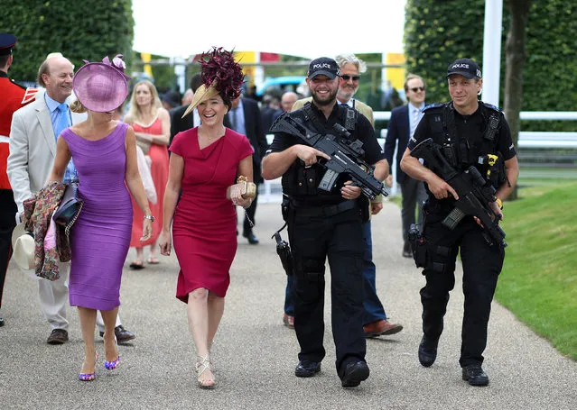 Two racegoers get an armed escort into the Goodwood festival on day one of the Qatar Goodwood Festival at Goodwood racecourse on August 1, 2017 in Chichester, England. (Photo by John Walton/PA Wire)