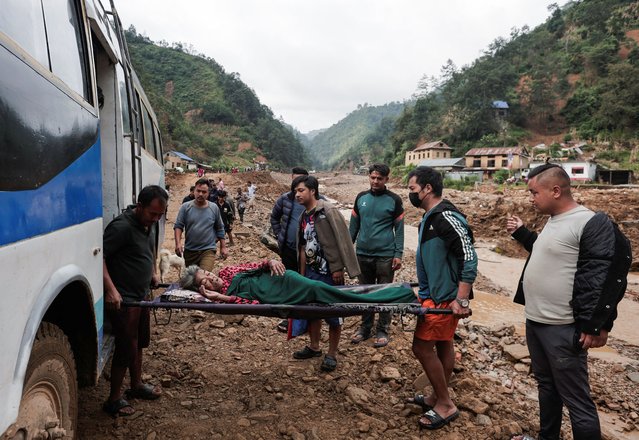 Tiuri Maya Tamang, 87, is taken inside a bus after being carried by the locals from her village as she heads to the hospital for a regular checkup, after the deadly floods following heavy rainfall, in Bethanchowk, Kavre, Nepal on October 4, 2024. (Photo by Navesh Chitrakar/Reuters)