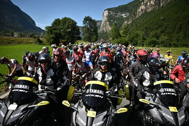 The pack of riders is temporarily immobilized by race regulators (front) due to protest action on the race route during the 10th stage of the 109th edition of the Tour de France cycling race, 148,1 km between Morzine and Megeve, in the French Alps, on July 12, 2022. (Photo by Marco Bertorello/AFP Photo)