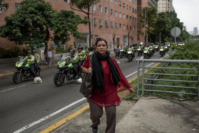 A woman runs form police officers during an attempt to march to the headquarters of the national electoral body, CNE in Caracas, Venezuela on May 18, 2016. (Photo by Alejandro Cegarra/The Washington Post)