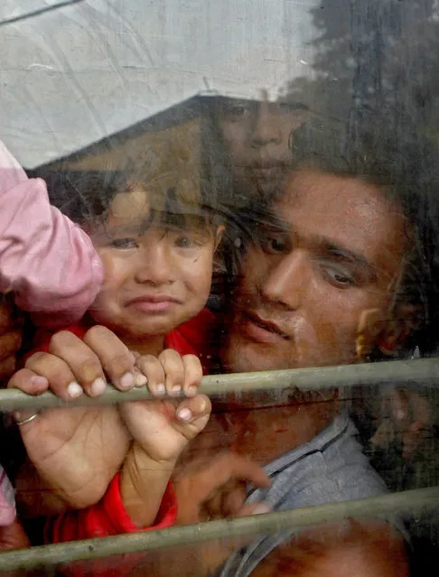 Migrants look out of a window onboard a crowded train taking them towards Serbia, at the railway station in the southern Macedonian town of Gevgelija, on Sunday, August 16, 2015. (Photo by Boris Grdanoski/AP Photo)