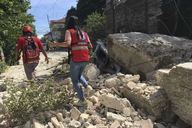 In this handout photo provided by the Philippine Red Cross, Red Cross volunteers walk along a collapsed wall after a strong earthquake hit Ilocos Sur province, Philippines on Wednesday July 27, 2022. (Photo by Philippine Red Cross via AP Photo)
