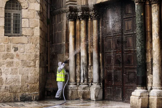 A worker disinfects the doors of the closed Church of the Holy Sepulchre in Jerusalem's Old City, as general public movements are limited to prevent the spread of coronavirus, Monday, March 30, 2020. (Photo by Mahmoud Illean/AP Photo)