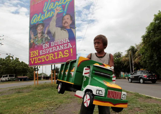 A boy carries his wooden toy truck as he walks past a billboard in support of Nicaragua's President Daniel Ortega and his wife Rosario Murillo in Tipitapa town, Nicaragua June 29, 2016. (Photo by Oswaldo Rivas/Reuters)
