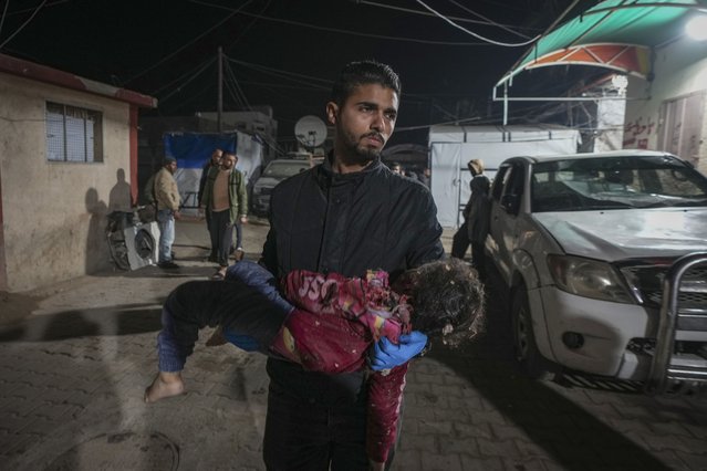 A man carries the body of child into the Al-Aqsa Martyrs hospital in Deir al-Balah, after an Israeli army strike in the Bureij refugee camp, central Gaza Strip, December 14, 2024. (Photo by Abdel Kareem Hana/AP Photo)