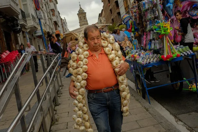 A man carries a strip of garlic during the garlic fair in Vitoria, northern Spain, Monday, July 25, 2016. Every year a traditional garlic market is set on the Saint James patron day gathering producers of all around Spain. (Photo by Alvaro Barrientos/AP Photo)