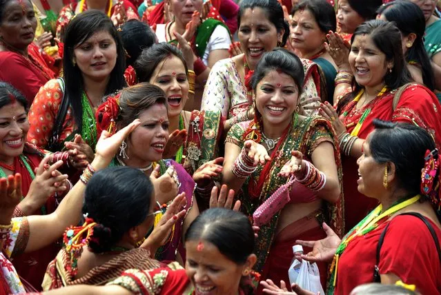 Nepalese Hindu women, dressed in red, dance after paying homage to Shiva, the Hindu god of destruction as they celebrate the Teej festival at the Pashupatinath temple area in Kathmandu on August 28, 2014. (Photo by Prakash Mathema/AFP Photo)