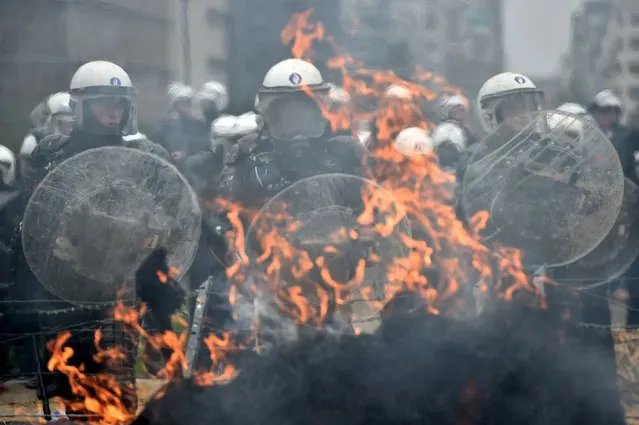 Police officers stand guard in front of a burning barricade as farmers and dairy farmers from all over Europe take part in a demonstration outside a European Union agricultural ministers' emergency meeting at the EU Council headquarters in Brussels, Belgium September 7, 2015. (Photo by Eric Vidal/Reuters)