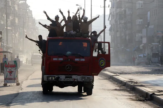 Syrian civil defence volunteers, known as the White Helmets, gather in a street in the northern city of Aleppo on August 6, 2016, in celebrations after rebels said they have broken a three-week government siege on Syria's second city. Rebel groups successfully broke the siege by opening a new route into the city from the southwest, opposition officials said. 
Opposition fighters, Islamists and jihadists have waged fierce assaults since July 31 to end the siege by government forces of some 250,000 people in Aleppo's eastern districts. Rebel and regime forces have fought for control of the provincial capital since mid-2012, transforming the former economic powerhouse into a divided, bombed-out city. (Photo by Thaer Mohammed/AFP Photo)