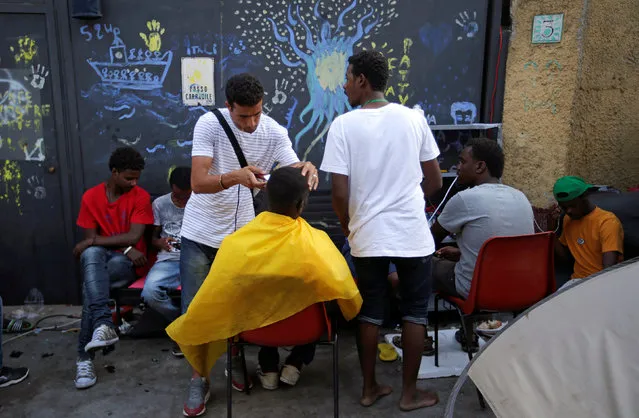 A migrant is getting a haircut from a volunteer at a makeshift camp in Via Cupa (Gloomy Street) in downtown Rome, Italy, August 1, 2016. (Photo by Max Rossi/Reuters)