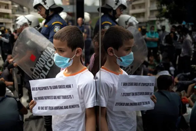 A boy wears a face mask as protection from the spread of the coronavirus disease (COVID-19) while refugees protest outside the UNHCR offices against a government decision that they should leave their accommodation provided through European Union and UNHCR funds by the end of May, in Athens, Greece, May 29, 2020. (Photo by Alkis Konstantinidis/Reuters)