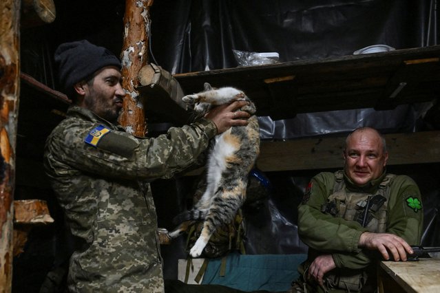 A serviceman of the 110th Territorial Defence Brigade of the Ukrainian Armed Forces holds a cat inside a dugout at a position on a frontline, amid Russia's attack on Ukraine, in Zaporizhzhia region, Ukraine on January 21, 2025. (Photo by Reuters/Stringer)