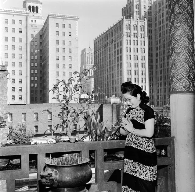 A Chinese woman at prayer in front of an incense burner on a balcony outside the main idol room in a temple in Chinatown, San Francisco, 1950. (Photo by Doreen Spooner)