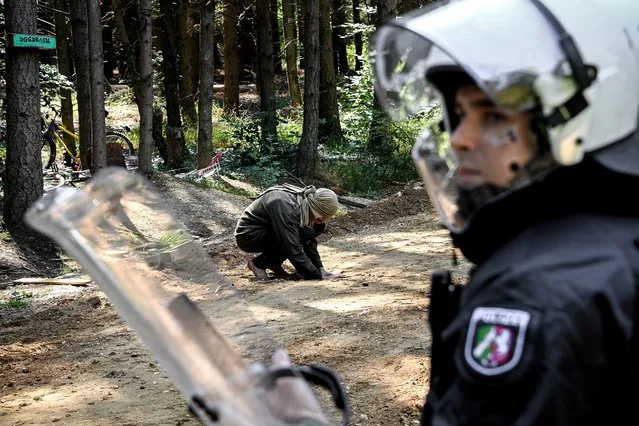 Police facing activists during a clearing operation in the Hambach Forest in Morschenich near Kerpen, Germany, 23 June 2020. The police have removed several barricades set up by environmental activists and have explicitly not cleared any tree houses. According to police, there are still about 100 squatters in the Hambach Forest. (Photo by Sascha Steinbach/EPA/EFE)