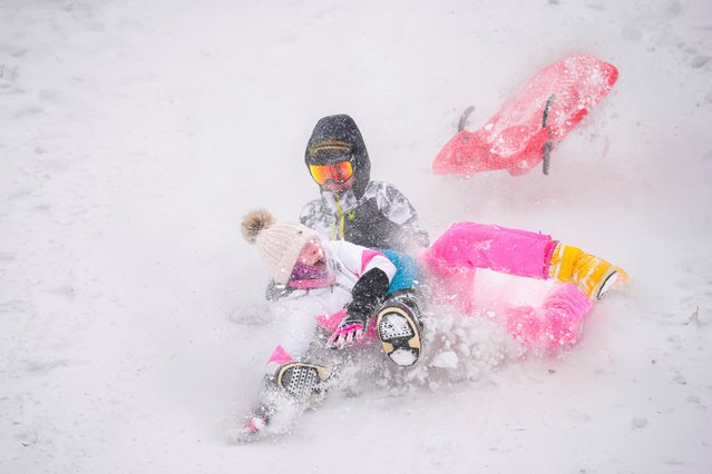 Children fall while riding a sled during a snowfall in Bucharest, Romania, Monday, February 17, 2025. (Photo by Vadim Ghirda/AP Photo)