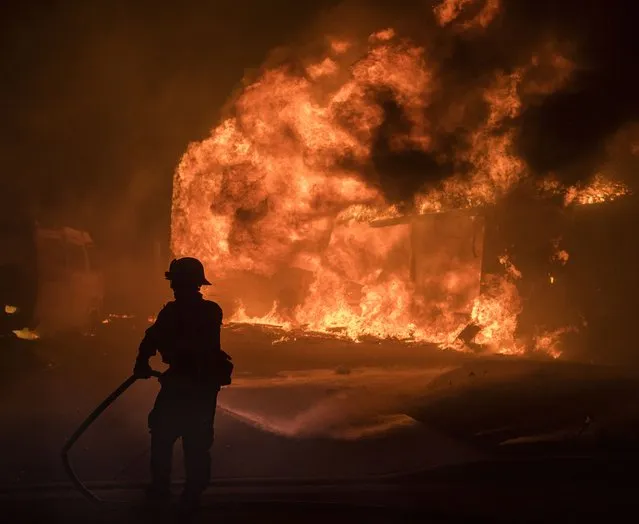 A firefighter works as a home burns during the “Thomas Fire” which began overnight  in Ventura, Calif., December 5, 2017. (Photo by John Cetrino/EPA/EFE/Rex Features/Shutterstock)